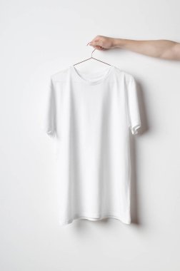Erkekler mürettebat boyun T-Shirt Mock-Up-beyaz bir t-shirt bir bakır tel elbise askısı üzerinde tutan adam