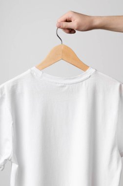 Erkekler mürettebat boyun T-Shirt Mock-Up-beyaz bir t-shirt üzerinde ahşap bir elbise askısı tutan adam