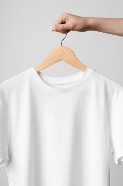 Erkekler mürettebat boyun T-Shirt Mock-Up-beyaz bir t-shirt üzerinde ahşap bir elbise askısı tutan adam