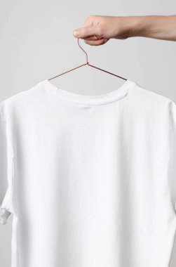 Erkekler mürettebat boyun T-Shirt Mock-Up-beyaz bir t-shirt bir bakır tel elbise askısı üzerinde tutan adam