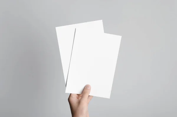 A5 Flyer / Invitation Mock-Up - Male hands holding blank flyers on a gray background.