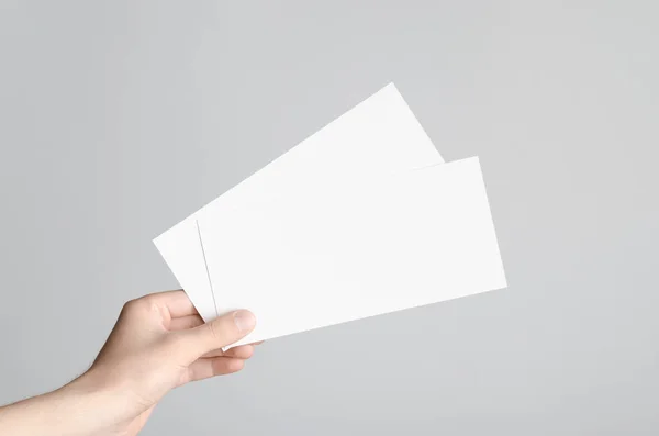 DL el ilanı Mock-Up-erkek elleri boş el ilanları gri bir arka plan üzerinde tutan.