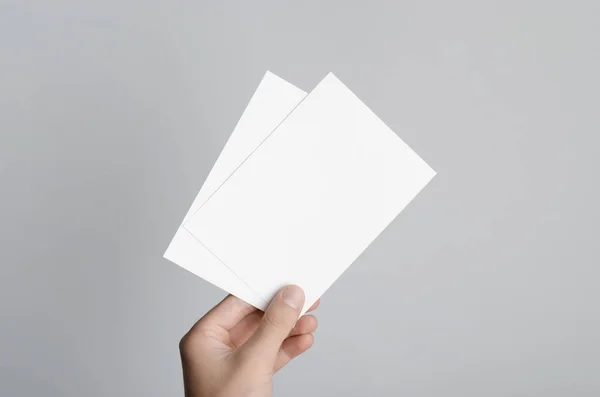 A6 el ilanı / kart / davet Mock-Up - boş el ilanları gri bir arka plan üzerinde tutan eller erkek.