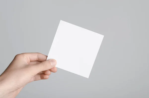 Square Flyer / Invitation Mock-Up - Male hands holding a blank flyer on a gray background.