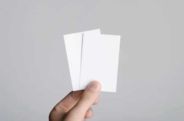 Business Card Mock-Up (85x55mm) - Male hands holding blank cards on a gray background.