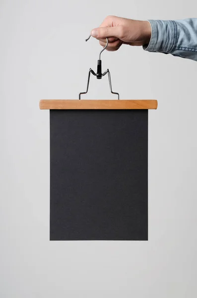 海报模拟 男子在一个白色的背景衣架上持有黑色海报 — 图库照片