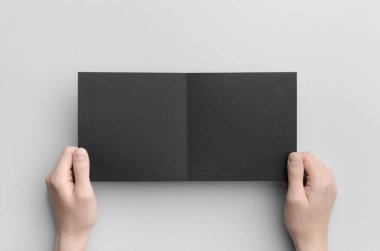 Siyah kare ikiye katlanmış broşür Mock-Up-gri bir arka plan üzerinde siyah bir ikiye katlanmış holding erkek eller.