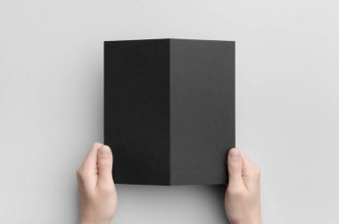 Gri bir arka plan üzerinde siyah bir ikiye katlanmış tutarak erkek siyah Dl ikiye katlanmış broşür Mock-Up - eller.