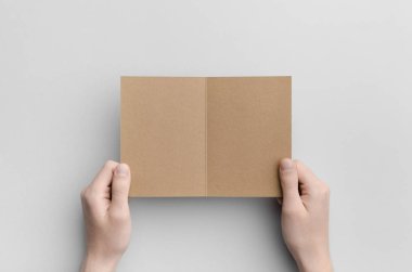 Kraft A6 ikiye katlanmış / yarı katlı broşür Mock-Up - erkek kraft ikiye katlanmış bir gri arka plan üzerinde tutan eller.