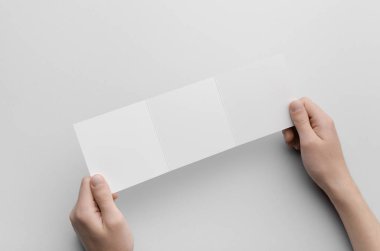 Kare üç katlı broşür Mock-Up - erkek boş üç katlı bir gri arka plan üzerinde tutan eller.