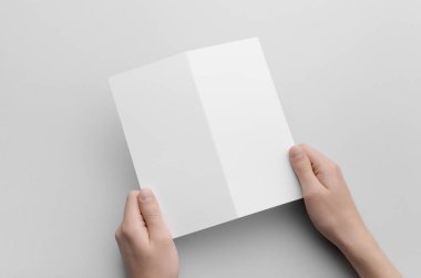 DL ikiye katlanmış broşür Mock-Up-gri bir arka plan üzerinde boş bir ikiye katlanmış holding erkek eller.