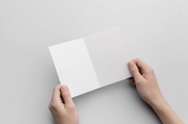 A6 ikiye katlanmış / yarı katlı broşür Mock-Up - erkek gri bir arka plan üzerinde boş bir ikiye katlanmış tutan eller.