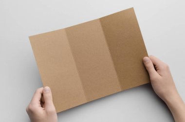 Kraft A4 üç katlı broşür Mock-Up - erkek kraft üç katlı bir gri arka plan üzerinde tutan eller.