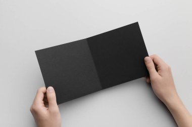 Siyah kare ikiye katlanmış broşür Mock-Up-gri bir arka plan üzerinde siyah bir ikiye katlanmış holding erkek eller.
