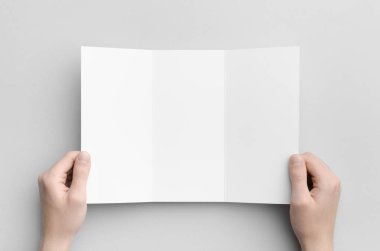 A4 Üç katlı broşür Mock-Up - erkek boş üç katlı bir gri arka plan üzerinde tutan eller.