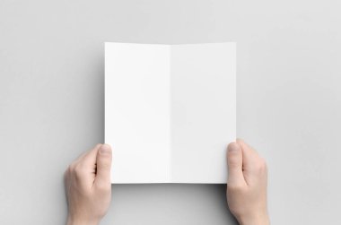 DL ikiye katlanmış broşür Mock-Up-gri bir arka plan üzerinde boş bir ikiye katlanmış holding erkek eller.