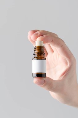 İlaç şişe Mock-Up. Boş etiket - gri bir arka plan üzerinde bir ilaç şişesi holding erkek eller