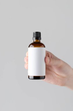 İlaç şişe Mock-Up. Boş etiket - gri bir arka plan üzerinde bir ilaç şişesi holding erkek eller