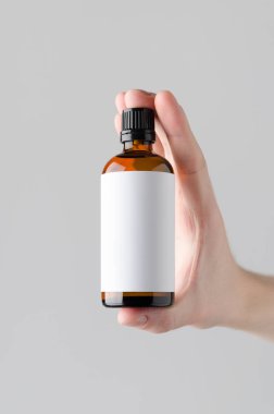 İlaç şişe Mock-Up. Boş etiket - gri bir arka plan üzerinde bir ilaç şişesi holding erkek eller