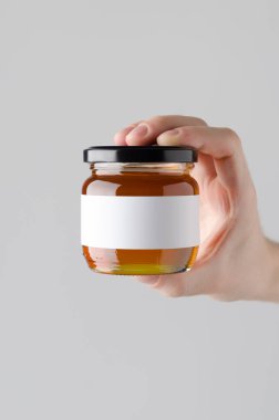 Bal kavanozu Mock-Up. Boş etiket - gri bir arka plan üzerine bal kavanozu holding erkek eller