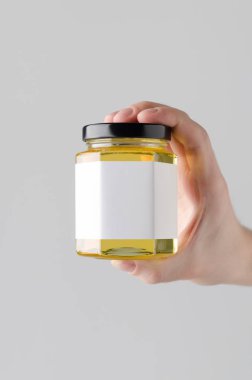 Bal kavanozu Mock-Up. Boş etiket - gri bir arka plan üzerine bal kavanozu holding erkek eller