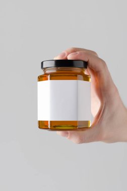 Bal kavanozu Mock-Up. Boş etiket - gri bir arka plan üzerine bal kavanozu holding erkek eller