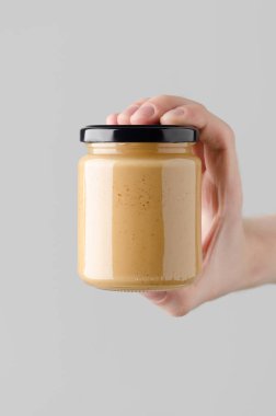 Fıstık / badem / fındık ezmesi kavanozu Mock-Up-fındık ezmesi holding erkek eller gri bir arka plan üzerinde kavanoz