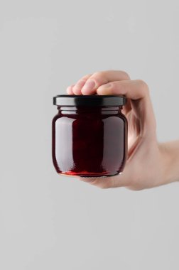 Kiraz reçel kavanoz Mock-Up-gri bir arka plan üzerinde bir reçel kavanoz holding erkek eller