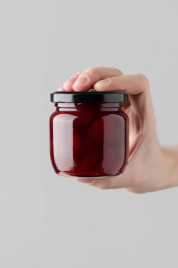 Çilek reçel kavanoz Mock-Up-gri bir arka plan üzerinde bir reçel kavanoz holding erkek eller