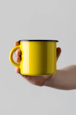 Sarı Emaye kupa Mock-Up - erkek bir emaye kupa gri bir arka plan üzerinde tutan eller