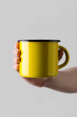 Sarı Emaye kupa Mock-Up - erkek bir emaye kupa gri bir arka plan üzerinde tutan eller