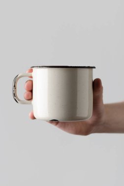 Beyaz emaye kupa Mock-Up - erkek bir emaye kupa gri bir arka plan üzerinde tutan eller