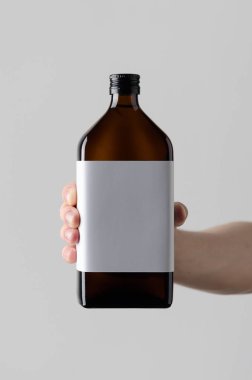 İlaç şişe Mock-Up. Boş etiket - gri bir arka plan üzerinde bir ilaç şişesi holding erkek eller