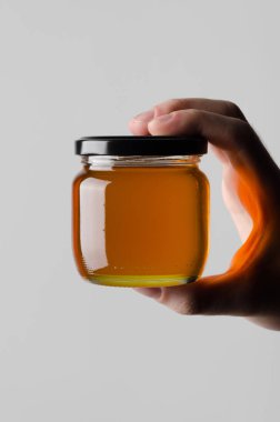 Bal kavanozu Mock-Up-gri bir arka plan üzerine bal kavanozu holding erkek eller