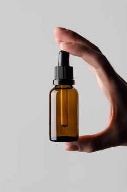 Damlalık şişe Mock-Up - erkek bir damlalık şişe gri bir arka plan üzerinde tutan eller