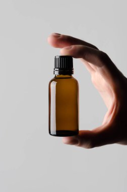 Damlalık şişe Mock-Up - erkek bir damlalık şişe gri bir arka plan üzerinde tutan eller