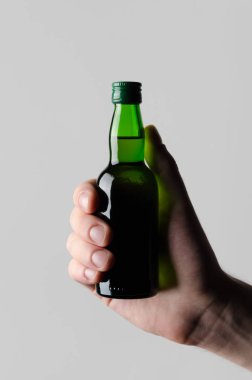 Minyatür alkollü içki şişesi Mock-Up - erkek eller gri bir arka plan üzerinde bir içki şişesi holding /
