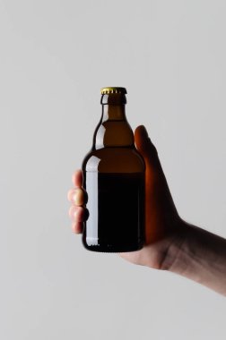 Bira şişe Mock-Up-gri bir arka plan üzerinde bir bira şişesi holding erkek eller