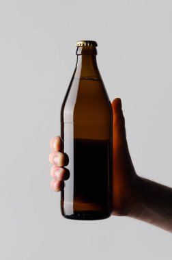 Bira şişe Mock-Up-gri bir arka plan üzerinde bir bira şişesi holding erkek eller