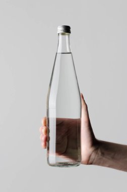 Su şişesi Mock-Up - erkek gri bir arka plan üzerinde bir su şişesi tutan eller