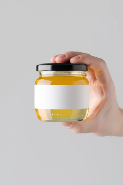 Honey Jar Mock-Up. Blank Label - Male hands holding a honey jar on a gray background