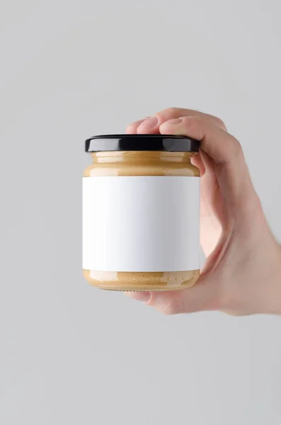 Peanut / Almond / Nut Butter Jar Mock-Up. Blank Label - Male hands holding a nut butter jar on a gray background