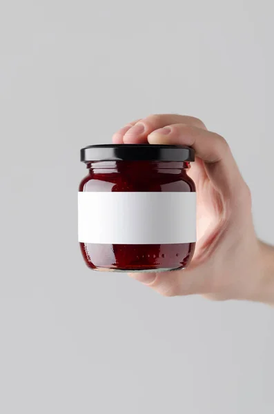 Strawberry Jam Jar Mock-Up. Blank Label - Male hands holding a jam jar on a gray background