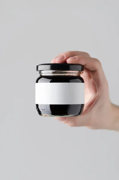 Blackberry Jam Jar Mock-Up. Blank Label - Male hands holding a jam jar on a gray background