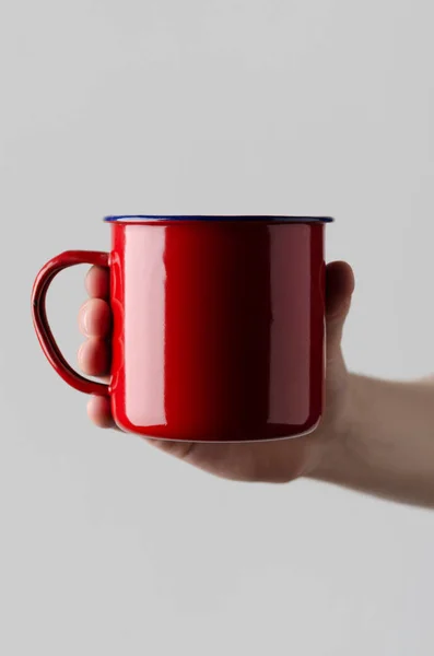 Red Enamel Mug Mock-Up - Male hands holding an enamel mug on a gray background