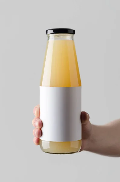 ジュース ボトルのモックアップ 空白のラベル 灰色の背景にジュースの瓶を保持している男性の手 — ストック写真