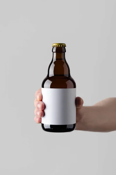 Beer Bottle Mock-Up. Blank Label - Male hands holding a beer bottle on a gray background