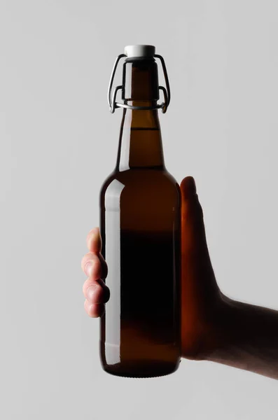 ビール瓶モックアップ 灰色の背景にビール瓶を持って男性の手 — ストック写真