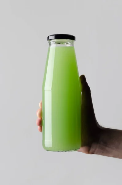 Juice Bottle Mock-Up - Male hands holding a juice bottle on a gray background