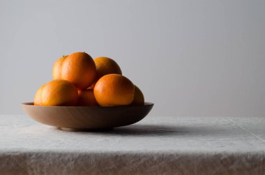 Portakal beyaz keten masa örtüsü üzerinde ahşap bir kasede.